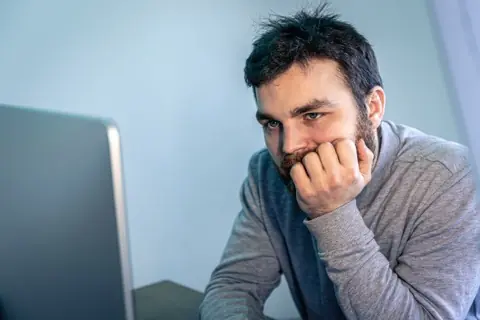 Bearded man staring at the computer screen, worried