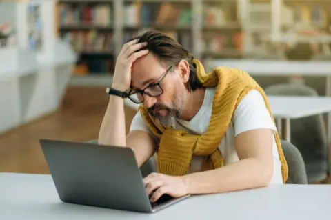Tired man with his hand on his head in front of the laptop